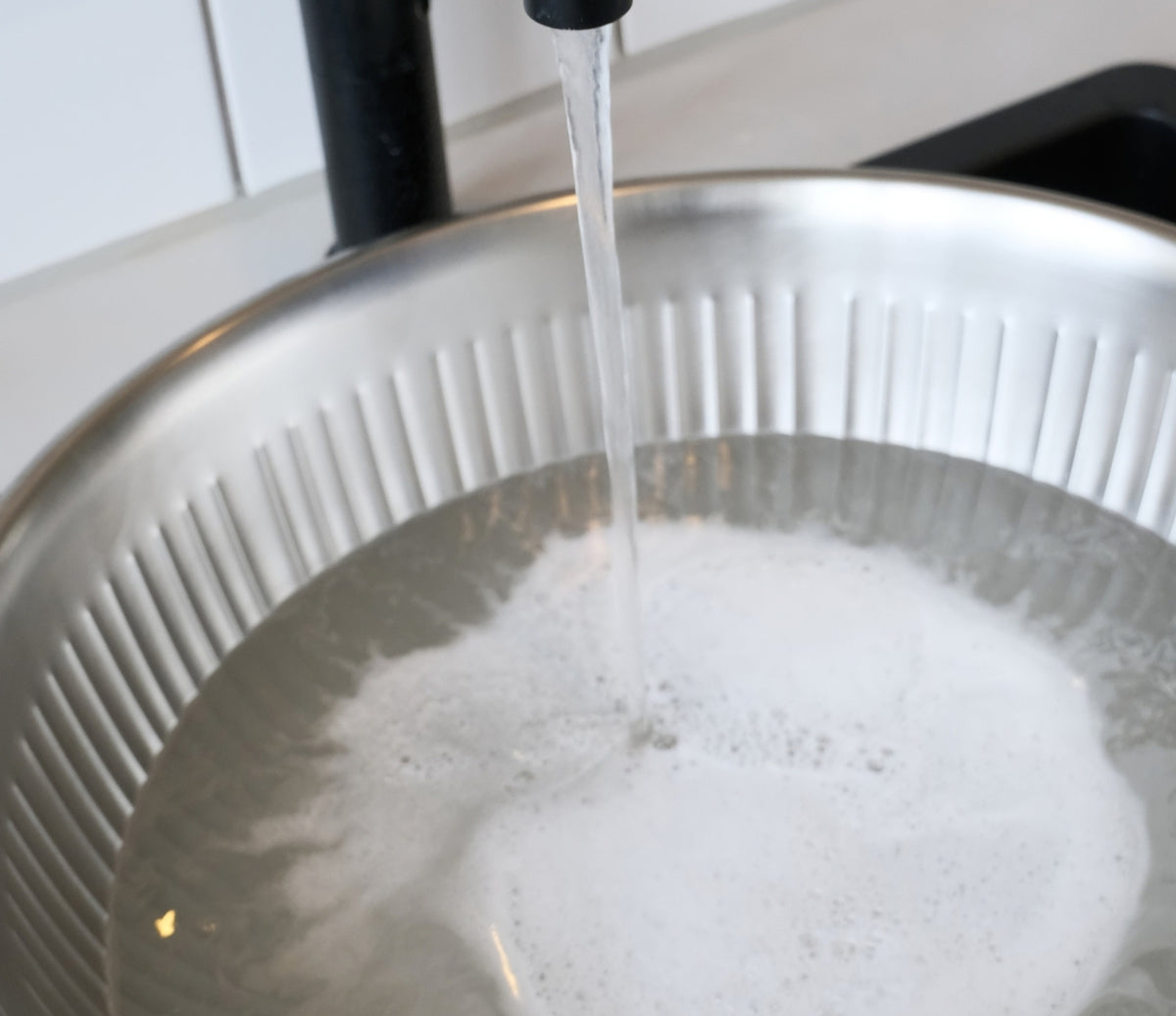 Image of a hand wash basin filled with water and detergent, ready for washing the knit sweater