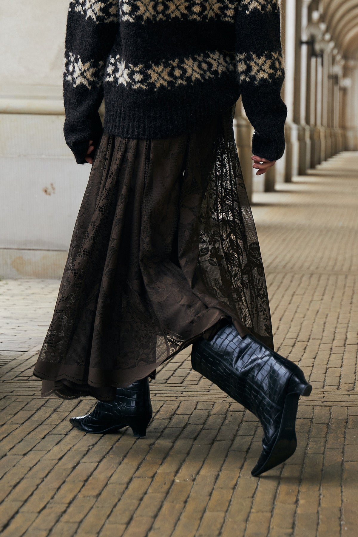 Woman wearing a brown Nordic-inspired knit with a brown lace skirt and black boots in Copenhagen.