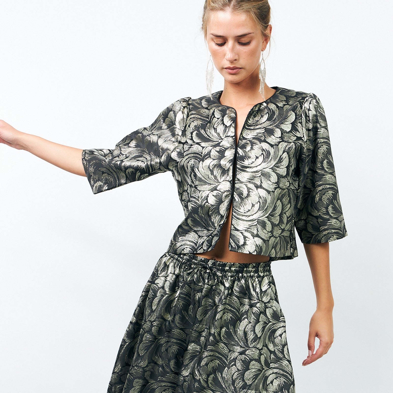 Model wearing a metallic jacquard jacket and skirt set with a leaf pattern – a cropped jacket with half sleeves and a matching elastic-waist skirt from Lollys Laundry.